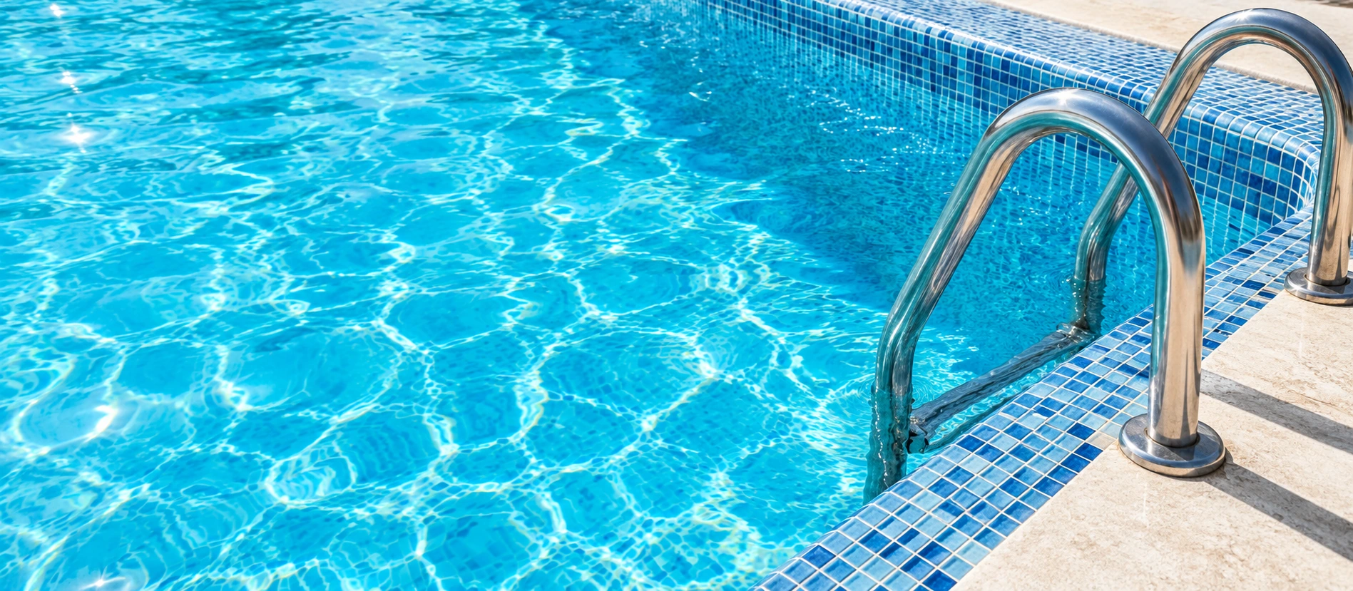 Escalera de acero y mosaicos junto al agua de una piscina
